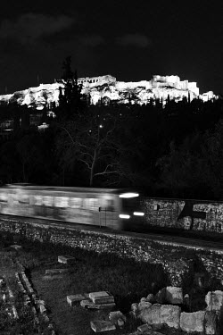 A metro train runs beneath the Acropolis, as seen from Ermou.