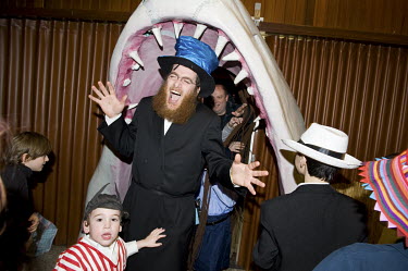 A rabbi pretends to be eaten by a model shark at a party to celebrate the festival of Purim.