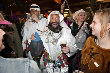 A man attendinga carnival ball dressed as an Muslim (Arab) terrorist wearing a suicide belt and carrying a bomb.