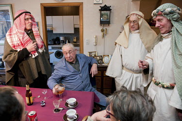 Three men dressed as the Biblical 'Three Kings' share a drink in a house as they follow a Christmas tradition of dressing up and going door-to-door to sing and drink.