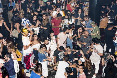 People drink, smoke and dance at a nightclub.