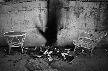 An old chair and table next to a fire made to keep themselves warm by vendors at a flea market.