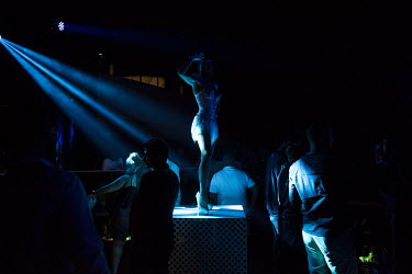 A woman at a nightclub dances on a podium.