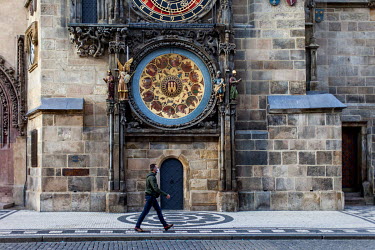 A man wearing a face mask passing the Astronomical clock in the Old Town Square. As of 21 October 2020 it is manditory for people to wear face masks both inside and out.