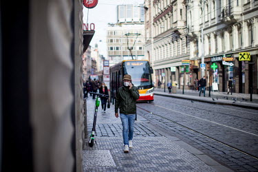 A man wearing a face mask walking in the city centre while making a mobile phone call. As of 21 October 2020 it is manditory for people to wear face masks both inside and out.