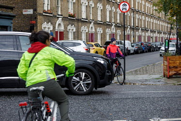 Cyclists wait for cars to pass before crossing a road in Walworth.