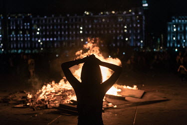 A woman stands watching a fire made out of wood barriers, aerosol spray cans, banners and bras in the Zocalo Plaza on International Women's Day. The annual demonstrationÂ�intensified and turned into...
