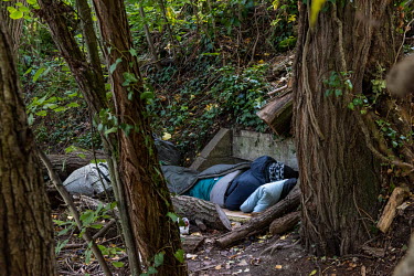 A homeless Nigerian man sleeps on concrete culvert, the only flat spot on the steep banks of the Avre River, behind the Queue d'Avre sport complex. The trees and undergrowth growing on the bank mean t...
