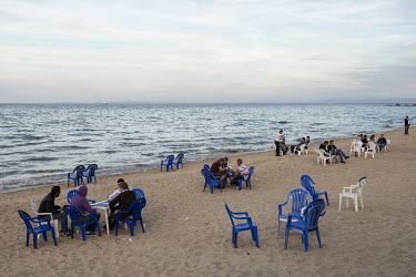 Groups of men sit together and socialise at sunset on Annaba beach.
