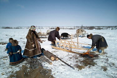 Nenets men hardening new sledge runners with fire as they prepare to migrate ('kaslanie') to a new camp for better grazing for their reindeer. In the spring they travel for several days over long dist...
