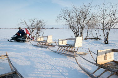Eyko, a Nenets activist who flies a communist party flag from his snowmobile, pulls a line of newly built sleighs he has bought for himself and others. He created an internet media site called 'Golos...