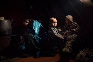 Nenets children Gosha and Tisha playing inside their tent ('chum') while their mother cooks on the stove.