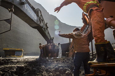 Company staff attempt to retrieve mining vehicles that are stuck in the mud at a jade mining site where the collapse of a huge lake of sludge killed at least 55 workers from the companies operating at...