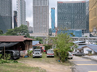 A low rise Malay kampung (traditional housing compound) area next to a highway and a commercial construction site.