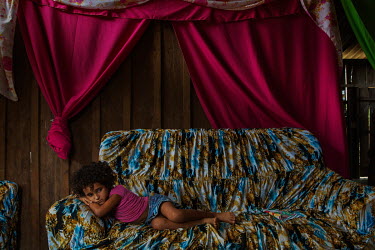 The daughter of a settler from the Sustainable Development Project Esperanca, rests on the sofa in her home.