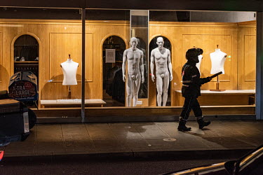 A Domino's Pizza delivery man passing a clothing shop on Rue des Paquis where bare mannequins stand in its windows. During the second wave of the COVID-19 pandemic restaurants and non-essential shops...