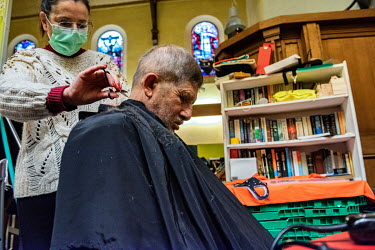 A homeless Romanian man receiving a free haircut from a volunteer at a local charity which is helping people from a church in the Paquis district.