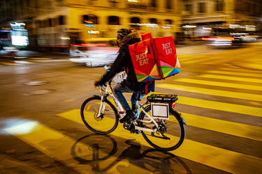 A Just Eat delivery man rides a bicycle along the Rue de Berne, in Geneva's multi-cultural Paquis district during the second wave of the COVID-19 pandemic which saw restaurants and non-essential shops...