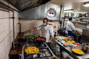 Ash, cooking the day's thali in the kitchen under his restaurant, Le Dhaba, during Geneva's second lockdown, in which restaurants were forced to close again. Behind him is his assistant and sole emplo...