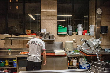 Andriulo prepares a pizza for take away as he works alone in his restaurant's kitchen during Geneva's second lockdown. Restaurants have been permitted to stay open, but only for take away service. And...