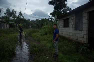 Jesus Jimenez (right), 22, and Gilberto Camposeco, 48, members of the community security committee of La Trinidad, carry out a security round as the Fuego Volcano looms in the background. While most o...