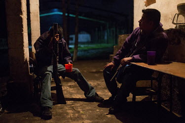 Celestino Montejo (left), 43, and Estuardo Lorenzo, 37, members of the community security committee of La Trinidad, take a break at the main outpost in between evening security rounds. While most of t...