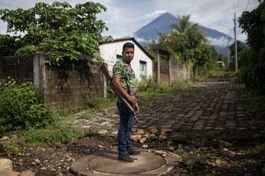 Enner Vidal Lorenzo, 24, member of the community security committee of La Trinidad, poses for a photo during a security round as the Fuego volcano looms in the background. While most of the 235 famili...