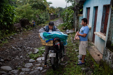 Berli Perez (right), 28, born in Chiapas, Mexico, while people from the 15 de Octubre La Trinidad community were there as war refugees, buys bread for dinner from salesman who bakes the bread in the t...