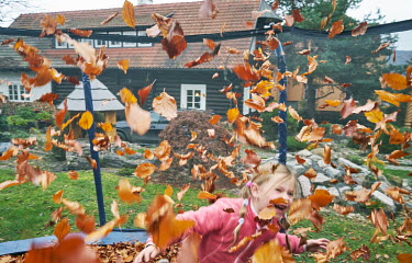 A girl plays with autumn leaves.