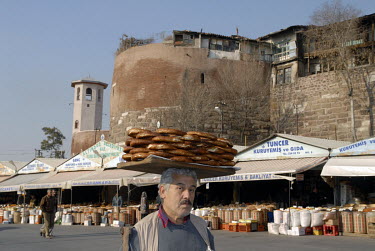 A man sells bread (simit) in a market place beneath the Finger Gate or Clock Gate, one of the gates to the Citadel or Hisar.
