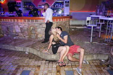 A young couple kissing on in a nightclub at the end of the night.