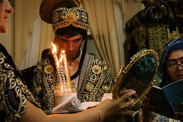 After ushering the bride to the ceremonial curtain, Mukhsram, a Koranic celebrant, leads call-and-response prayers with the groom, Behzod, and female wedding guests. Behzod slowly makes his way to the...