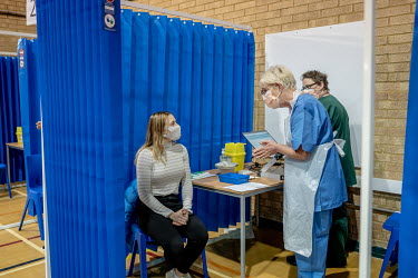 Katherine Carnegie, a junior doctor working in accident and emergency, prepares to receive the Pfizer/Biontec COVID-19 vaccination at the Cardiff and Vale Therapy Centre.