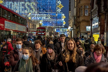 Crowds of people out Christmas shopping on Oxford Street pass below the festive lights.
