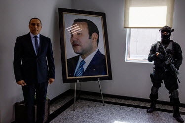 Abdelhak El Khayam, the director of the Bureau Center d'Investigation Judiciaire, which deals with cases of Islamised terrorism, beside a large portrait of King Mohammed VI and a heavily armed guard.