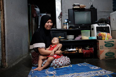 Siti Raudoh with the youngest of her three children at her home in Tangerang. Her husband, Iskandar, a security guard, died from snake a bite after his finger was grazed by the fang of a snake that he...