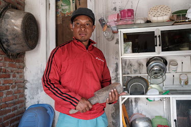 Kus Hariyanto in his family's kitchen at their home on the outskirts of Surabaya. He was almost blinded by a spitting cobra that appeared amongst the dishes on the rack behind him. Fearing for his you...