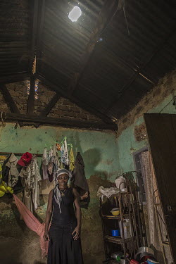 A woman's home illuminated by a lamp made using a plastic soft drinks bottle filled with water and a few drops of bleach and fitted with a metal reflector. A hole is made in the tin roof and the bottl...