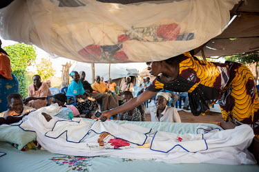 Poni (yellow, orange dress), removes the mosquito net that covered her dead sister in law Lily Ipayi at the end of the first day of her funeral ceremony. Lily (39) died on the morning (1am) of 5 Octob...