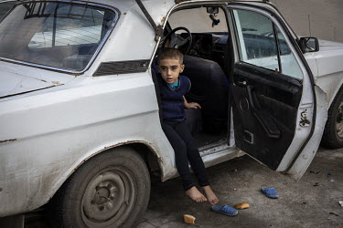 A young boy sits in a car outside a school in the city of Barda that has been turned in to a shelter for people who have been displaced by fighting in the frontline towns and villages around Terter an...