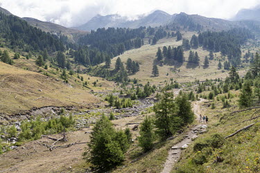 Hikers walk a trail towards Bric Bouchet mountain in Le Queyras National Park in the French Alps.
