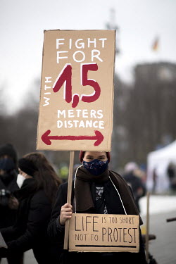 An activist with a placard that reads 'Fight for 1 point 5' at a protest, in front of the Brandeburger Gate, to mark the Paris Climate Agreement's 5th anniversary.