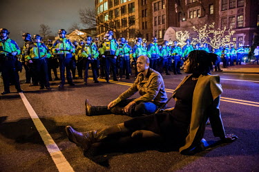 Two people sit in the road in front of a line of riot police on the day of Donald Trump's inauguration.