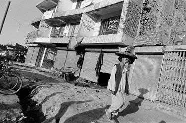 A bread (naan) seller walks down the street carrying his bread in a basket on his head.
