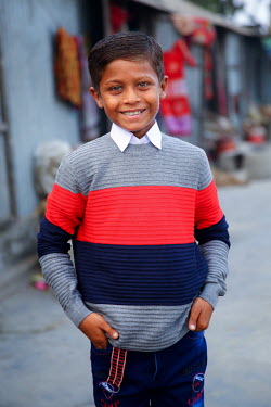 A boy wearing new clothes that were paid for by photographer G.M.B. Akash who is also sponsoring the boy so he has been able to stop labouring work and start to attend school for the first time.