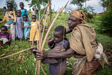 Francis Sembagare, a Batwa (pygmies) elder, teaches his child how to use a bow and arrow. Francis has known life in the rain forest, and tries to pass on old traditions, hunting techniques and knowled...