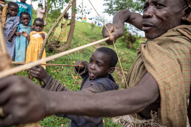 Francis Sembagare, a Batwa (pygmies) elder, teaches his child how to use a bow and arrow. Francis has known life in the rain forest, and tries to pass on old traditions, hunting techniques and knowled...