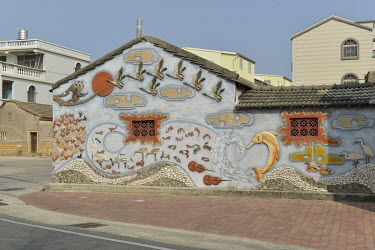Restored decorative scenes depicting wildlife found in the local wetlands on the exterior wall of a traditional residence in Husia Village.