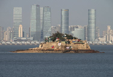 Shiyu Islet, a forward observation post controlled by the Taiwanese military, and the gleaming skyscrapers of Xiamen on the Chinese mainland beyond, seen from Xiao (Little) Kinmen Island.  Following t...