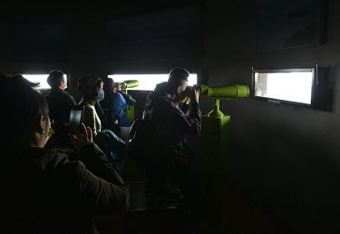 Taiwanese domestic tourists look at the coast of the Chinese mainland, just a few miles away, through high-powered binoculars at a military outpost on Xiao (Little) Kinmen.  Following the retreat of C...